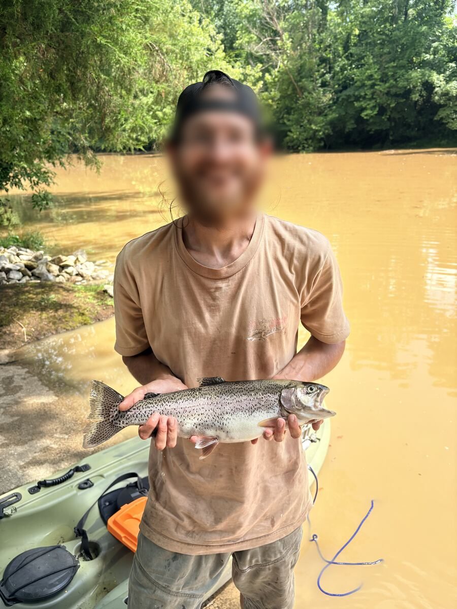 Smiling angler holding a rainbow trout on the Obey River